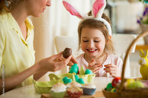 Wall Mural Mother and daughter celebrating Easter, eating chocolate eggs