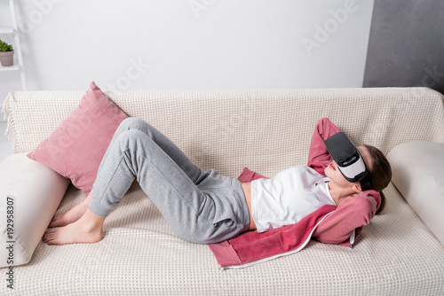 Wallpaper Mural high angle view of girl doing sits up with virtual reality headset on sofa at home Torontodigital.ca