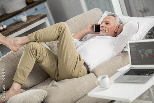 Have a break. Joyful worker expressing positivity while talking per telephone, being at home