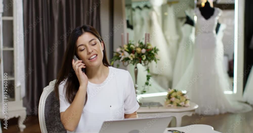 4K Business owner working on laptop & talking on phone in bridal wear boutique. Slow motion. 4K Business owner working on laptop & talking on phone in bridal wear boutique. Slow motion.