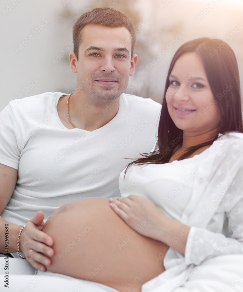 portrait of pregnant woman with husband sitting on the couch portrait of pregnant woman with husband sitting on the couch