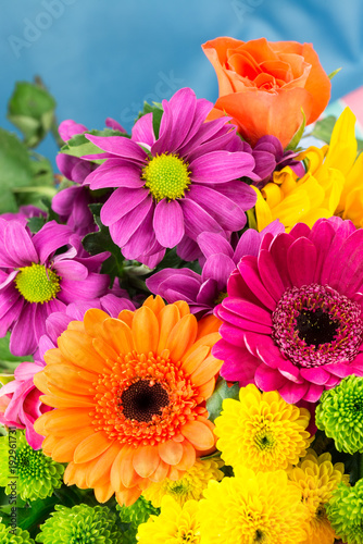 Bunch of fresh vibrant brightly coloured florist flowers with a blue background. Vertical.