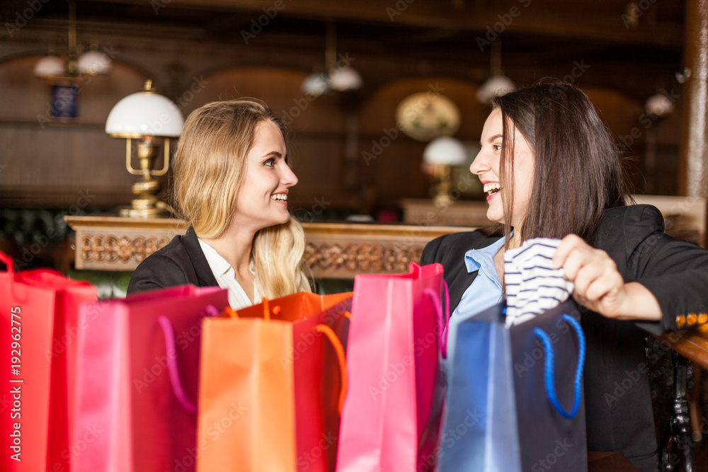 Smiling girls watch clothes they bough at supermarket Smiling girls watch clothes they bough at supermarket
