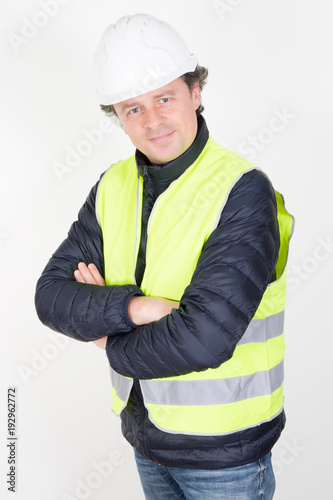 Studio shot of young happy man construction worker smiling with arms crossed