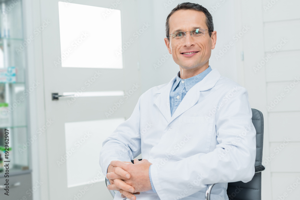 Smiling doctor with clenched hands in modern clinic