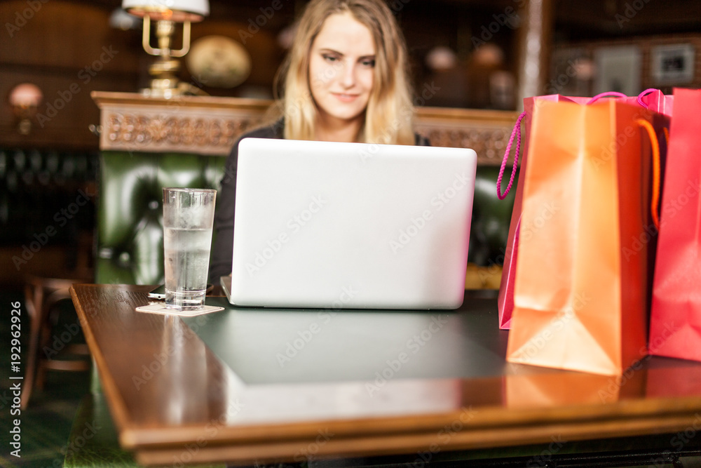 Smiling young female shops in internet for holiday gifts on cyber monday with presents in bags Smiling young female shops in internet for holiday gifts on cyber monday with presents in bags