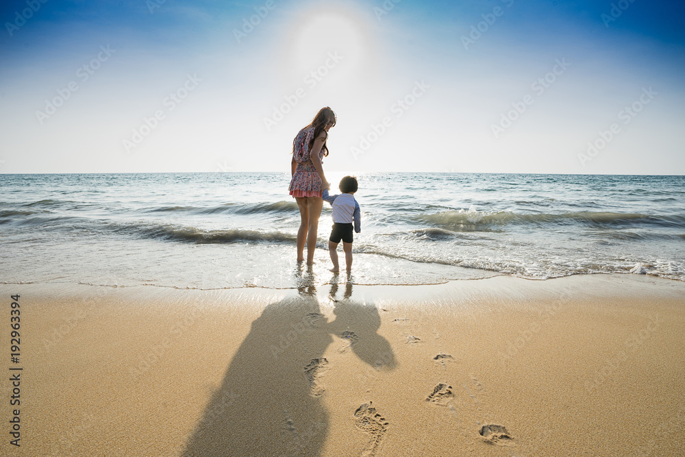 Mom walking on the beach with her son.