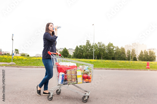 Young attractive girl drinks watere after hard trip of product buying photo