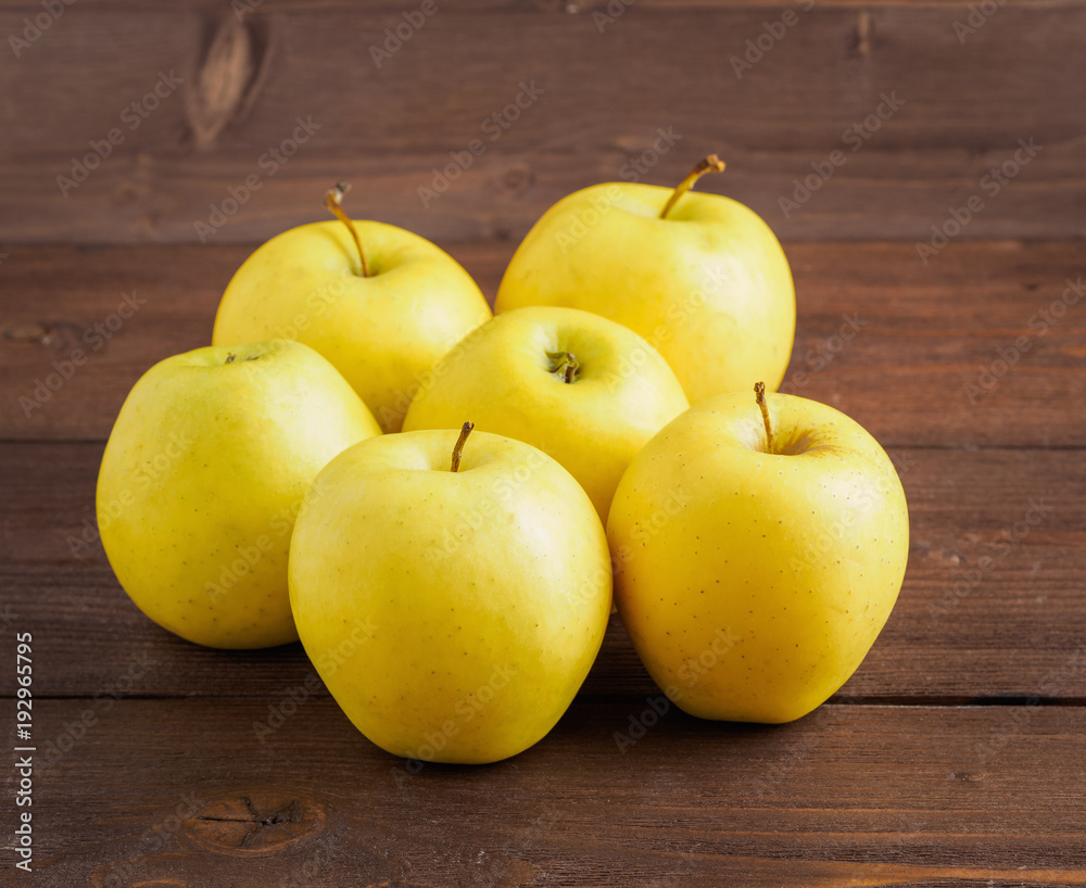 Golden Delicious. Juicy ripe fresh yellow apples on a brown wooden background, side view. Golden Delicious. Juicy ripe fresh yellow apples on a brown wooden background, side view.