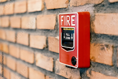 Close up fire alarm activation box on brick wall in room
