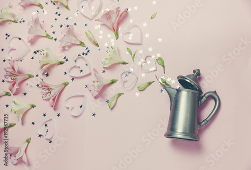 Magic spring appearance of flovers and hearts from vintage kettle on pink background. top view, flat lay. romantic spring picture photo