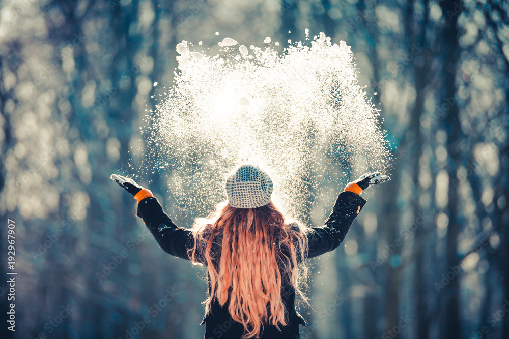 Young girl throwing snow in the air at sunny winter day, back view - obrazy, fototapety, plakaty 