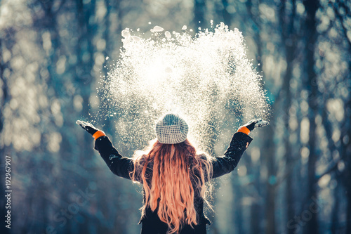 Młodej dziewczyny miotania śnieg w powietrzu przy pogodnym zima dniem, tylny widok