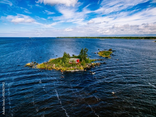 A small red cottage on an island in the blue sea on a summer day. Finland. View from above. photo