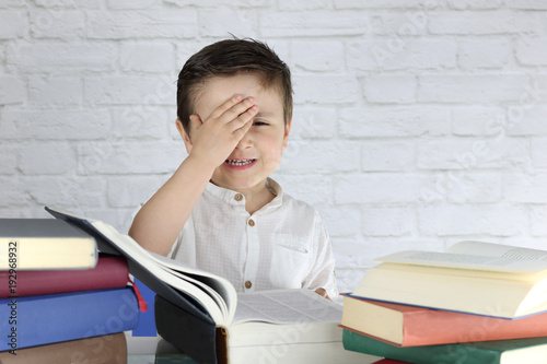 niño pequeño con cara de estres rodeado de libros photo