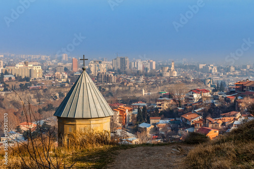 Old church dome with the cross and growing residential area with modern buildings, Tbilisi, Georgia