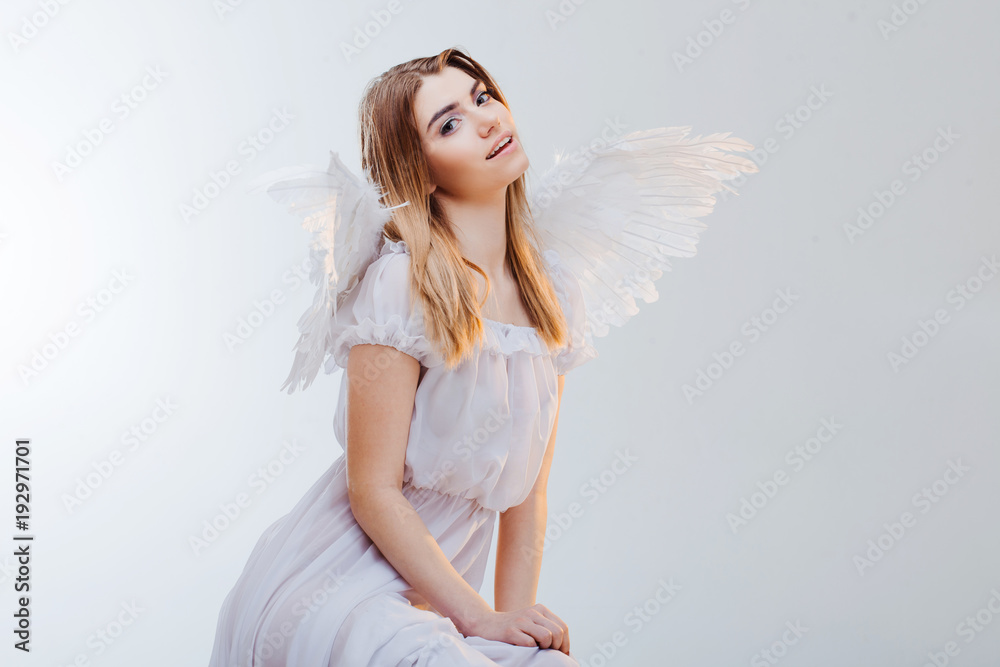 An angel from heaven. Young, wonderful blonde girl in the image of an angel with white wings. Portrait close-up An angel from heaven. Young, wonderful blonde girl in the image of an angel with white wings. Portrait close-up