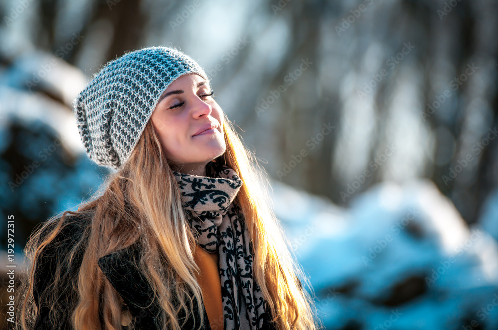 Fototapeta premium Young woman in the winter park at sunny day, warm clothes