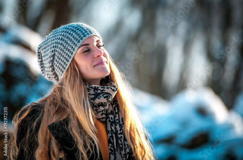 Young woman in the winter park at sunny day, warm clothes photo