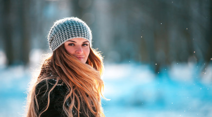 Young woman walking in winter park at sunny day