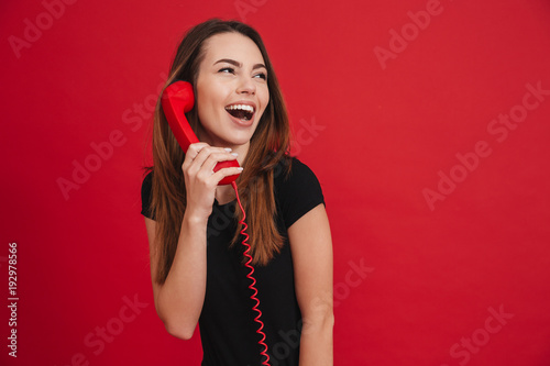 Portrait of a cheerful girl talking on a landline phone photo