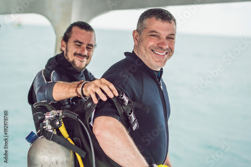 Fotografie Diving instructor helps a beginner diver prepare for diving