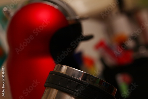 Stainless steel mug and coffee maker scene.