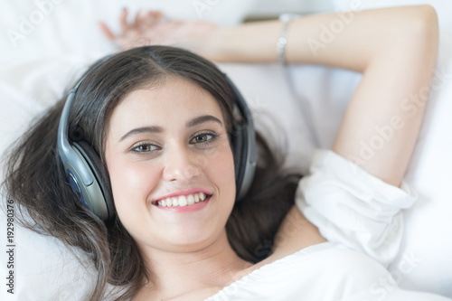 Charming woman on bed wearing headphones enjoy music.