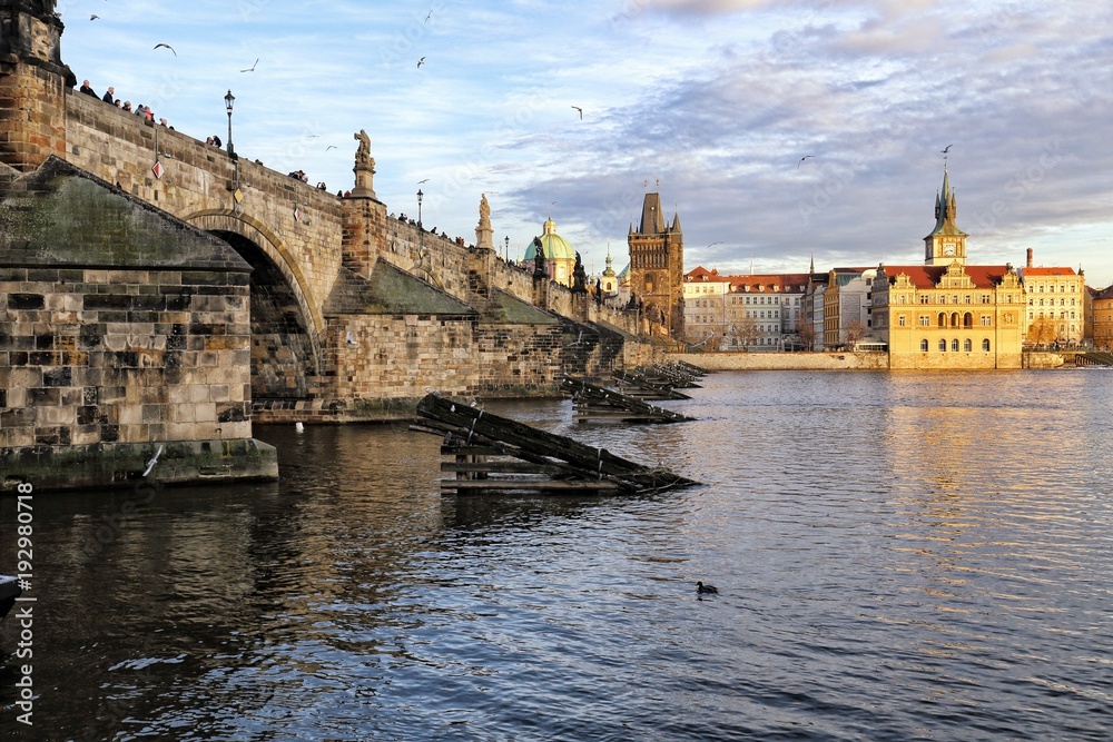 Prague Charles Bridge with the tower and buildings lit by evening sun