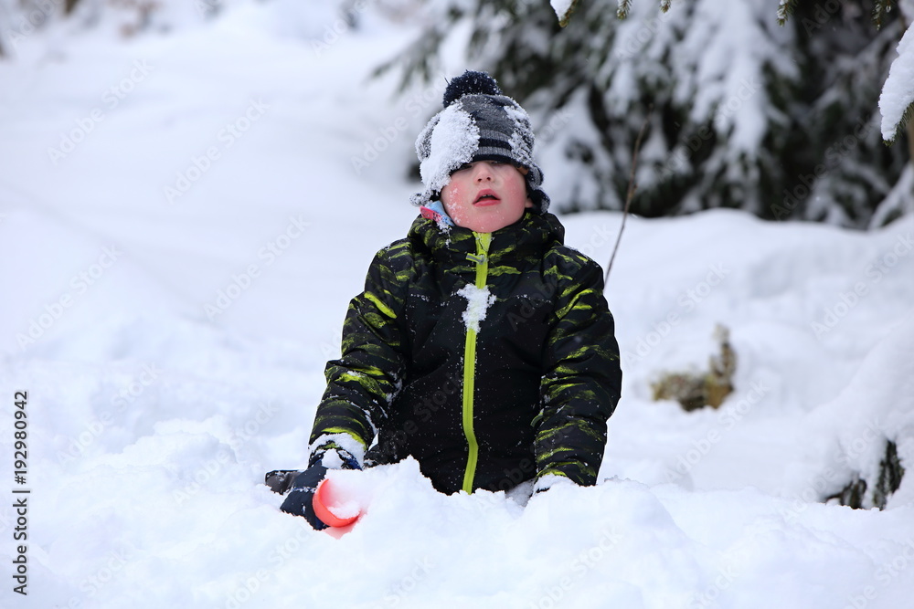 Kid playing in deep snow with red shovel