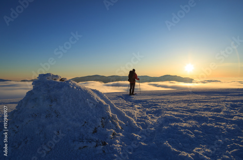 Hiker walking on snowshoes in the snowcovered mountains during a colorful, winter sunset. Vercors, France. © sanderstock