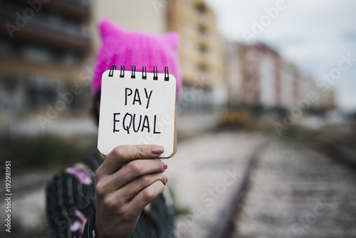 woman with a pink hat and the text pay equal