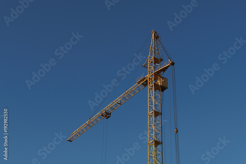Construction crane against on the clear blue sky background.