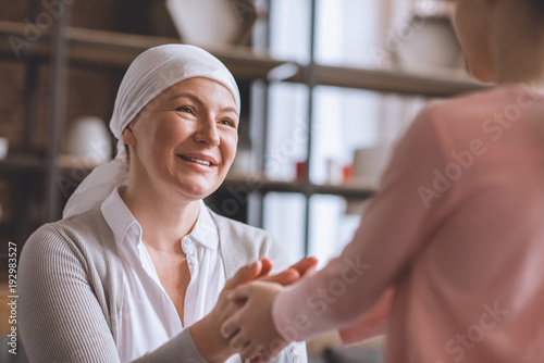 cropped shot of kid and sick smiling mature woman in kerchief holding hands photo