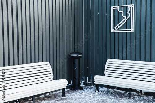 Zone for smoking with ash bin and wooden white benches. Permission for smoking in special place. Area for smokers to relax. Bad habit concept photo