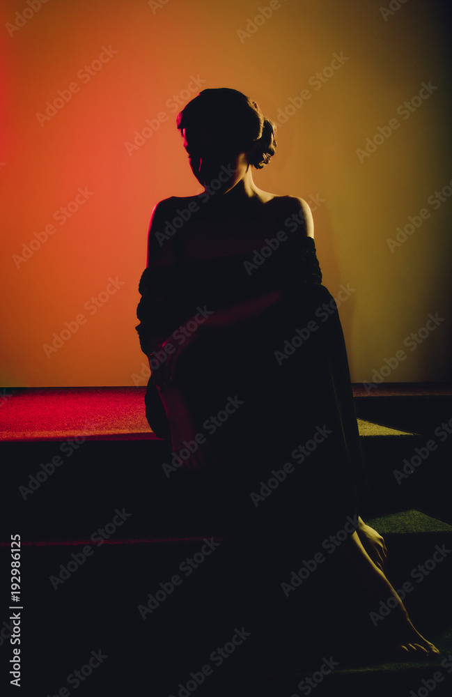 Dark black silhouette of elegant woman done in colorful lighting by photo filter gels.