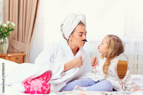 Mother and daughter in bathrobes and towels on the bed in the room. Mothers day. © Studio Romantic