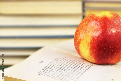 Fotografie A large red apple on an open book with Shakespeare's sonnets on the background o