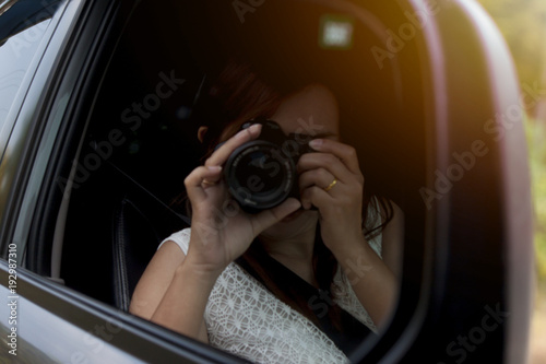 Women take photo by DSLR camera inside car.