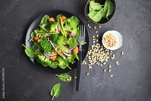 Vegetarian dinner snack salad of broccoli, young peas, baby carrots, sweet onions with pine nuts. Top View. photo