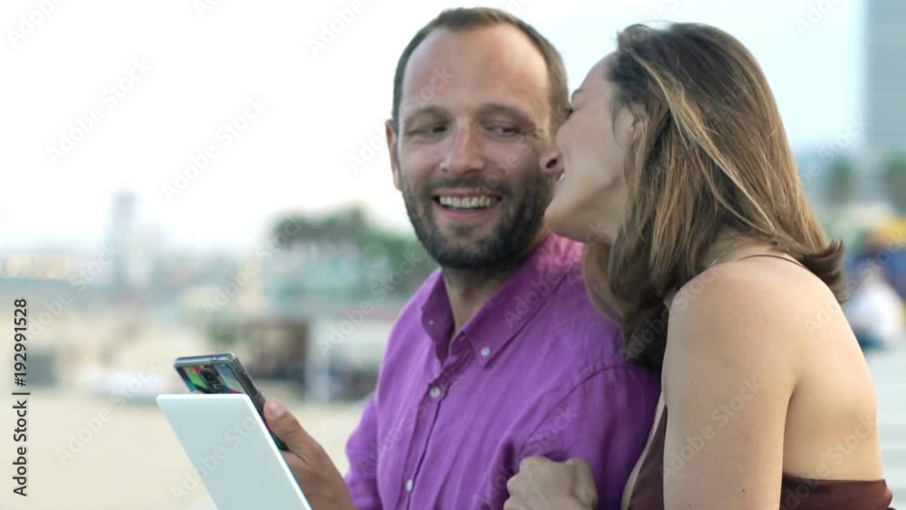 Young couple with smartphone and tablet talking near beach in city
Young couple with smartphone and tablet talking near beach in city