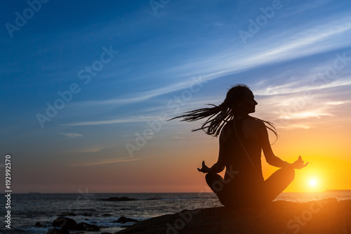 Yoga silhouette meditation woman on the Sea beach during amazing sunset. Healthy lifestyle.