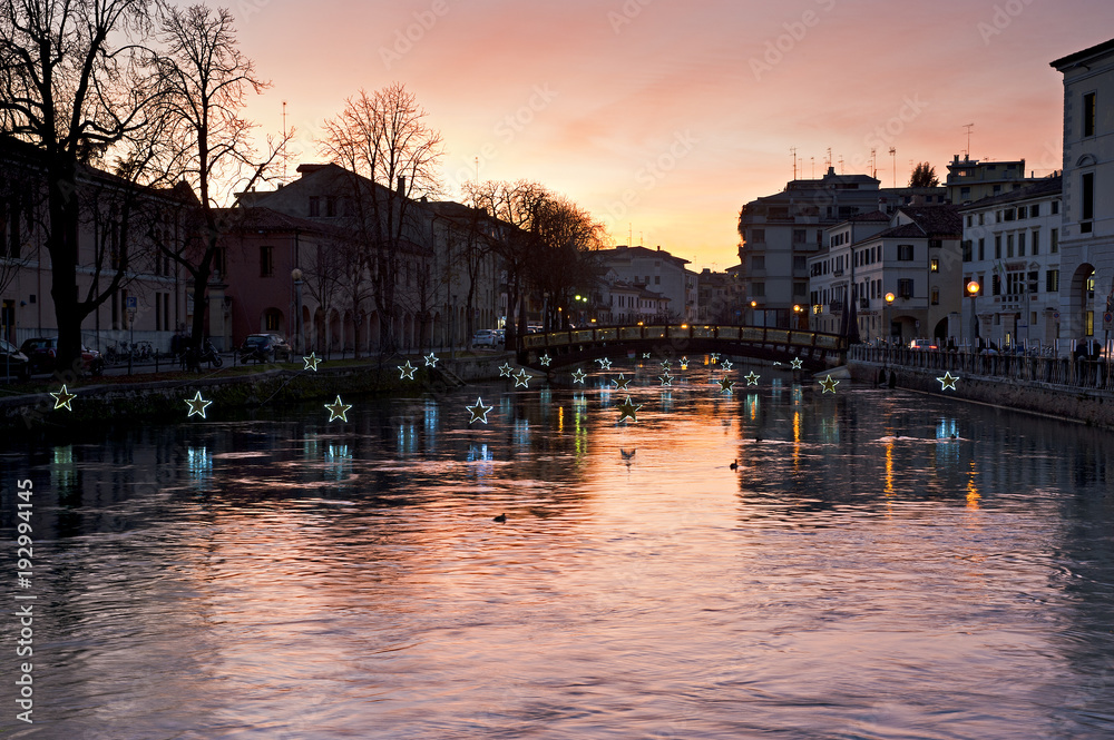 The river Sile decorated for Christmas, in the background the university bridge in Treviso. Italy