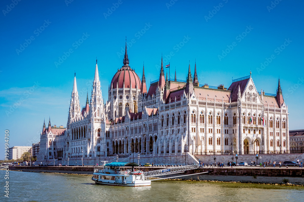 Parliament building in Budapest, Hungary, seen from the Danube river on a sunny day. 