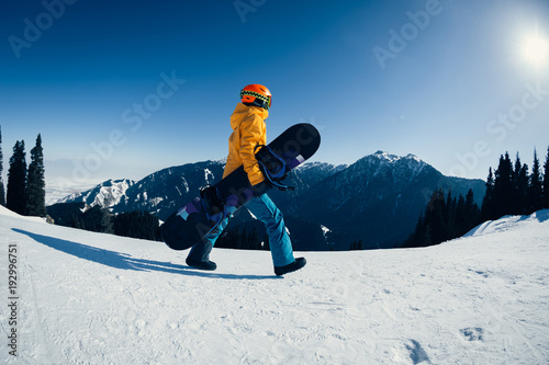 one snowboarder with snowboard walking on winter mountain peak