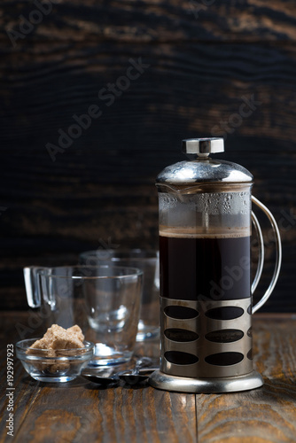 freshly brewed coffee in the french press on wooden table, vertical