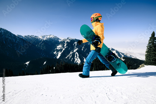one snowboarder with snowboard walking on winter mountain top