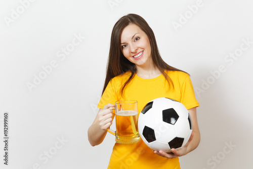 Beautiful European young cheerful woman, football fan or player in yellow uniform holding pint mug of beer, soccer ball isolated on white background. Sport, play football, healthy lifestyle concept. © ViDi Studio