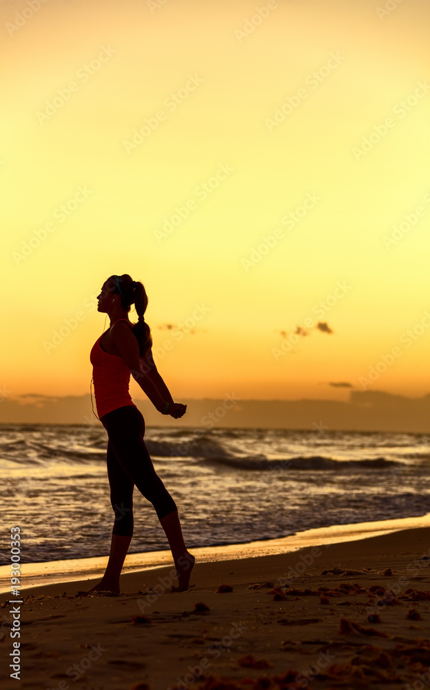 Silhouette of healthy woman in sportswear on seacoast stretching Silhouette of healthy woman in sportswear on seacoast stretching