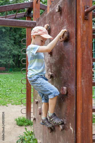 boy having fun and climbing on the outdoor playground.